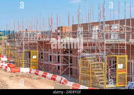 UK newbuild homes under construction surrounded by scaffolding on a sunny day. Stock Photo
