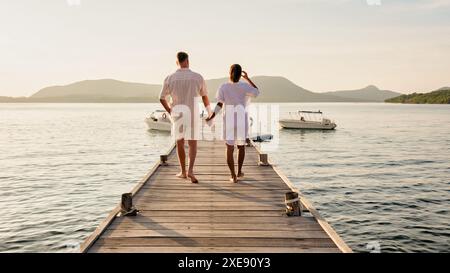 A man and a woman are standing on a dock holding hands Stock Photo