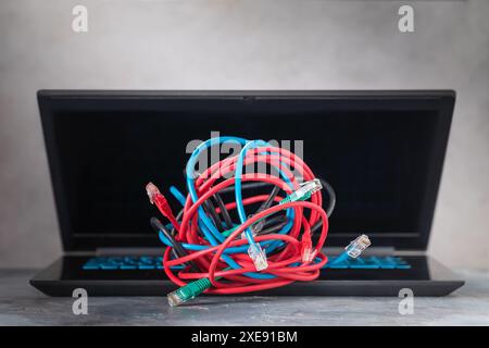 A pile of network computer wires on a laptop, a concept on the difficulty of connecting to a local network or the Internet Stock Photo