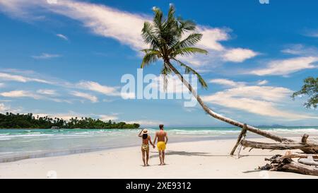 A man and a woman are standing on a beach under a palm tree at Koh Kood Thailand Stock Photo