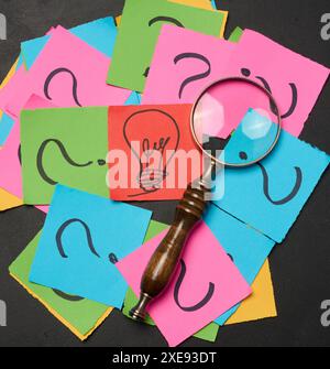 Drawn light bulbs on sheets of paper and a magnifying glass Stock Photo