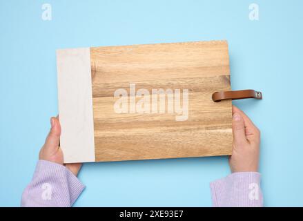 Female hand holding a rectangular wooden cutting board kitchen board Stock Photo