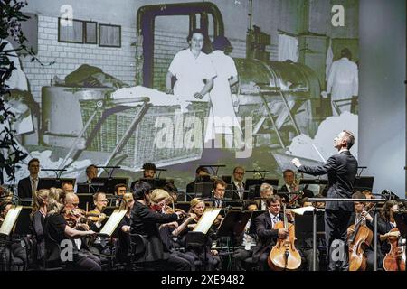 Cottbus, Germany. 26th June, 2024. General Music Director Alexander Merzyn (r) conducts the Cottbus State Theatre Philharmonic Orchestra at the ceremony to mark the 110th anniversary of the Carl-Thiem-Klinikum Cottbus. The 'Vereinigte Städtische und Thiemsche Heilanstalt' was inaugurated on June 27, 1914. Credit: Frank Hammerschmidt/dpa/Alamy Live News Stock Photo