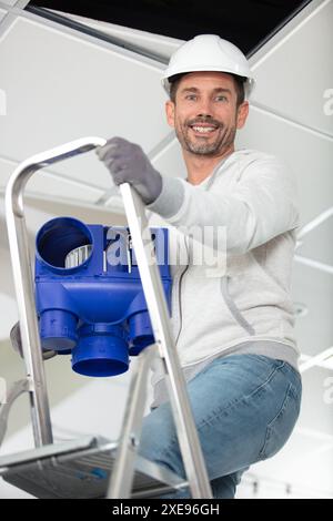 male contractor installing a ventilation system Stock Photo