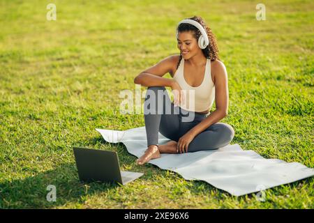 Woman in Activewear Listening to Headphones While Using Laptop Stock Photo