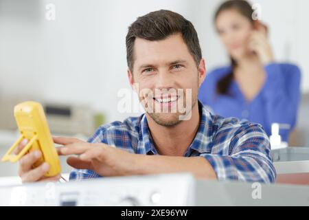 happy man checking socket voltage using multimeter Stock Photo