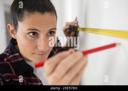 beautiful builder with measuring tape in new apartment Stock Photo