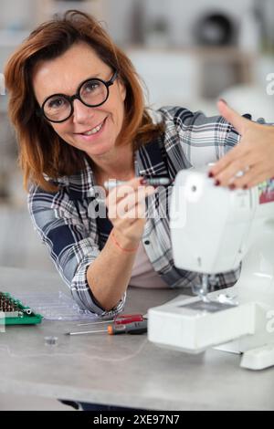 woman repairing sewing machine with a screwdriver Stock Photo