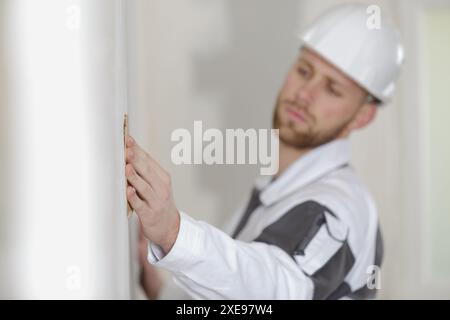 builder using sandpaper on interior wall Stock Photo