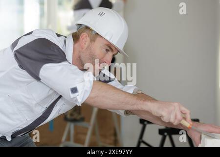 happy builder in hardhat plastering a wall Stock Photo