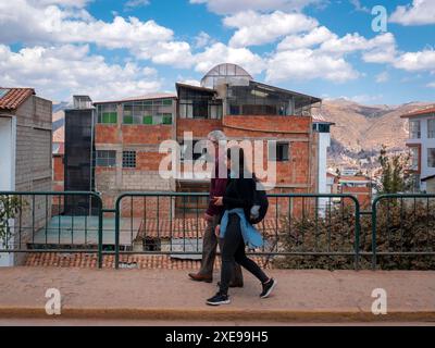 Black-Haired Woman walking with her Father Front of a lot oh Houses in Cusco, Peru Stock Photo