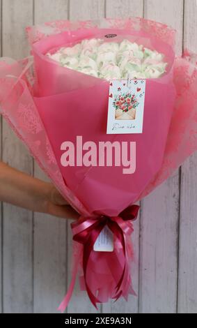 A marshmallow bouquet in the hand of a woman. Tulips from marshmallows. Bouquet in pink colors. Stock Photo