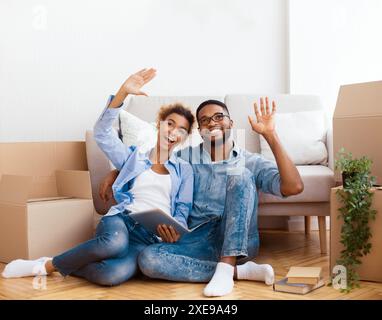 Couple Using Tablet Discussing Interior Ideas Sitting In New Home Stock Photo