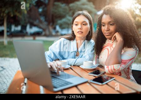 Two Women Working on Laptop at Outdoor Cafe Stock Photo