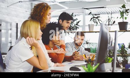 Young team analyzing new information, looking at computer Stock Photo