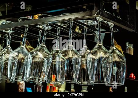 Wine glasses hanging from a stemware rack Stock Photo