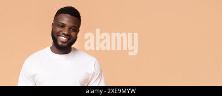 Smiling African American Man Wearing White T-Shirt Against Peach Background Stock Photo
