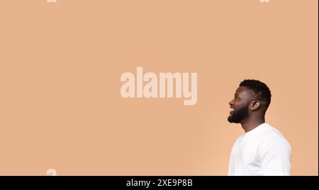 Smiling Black Man Looking Off Camera Against Peach Background Stock Photo