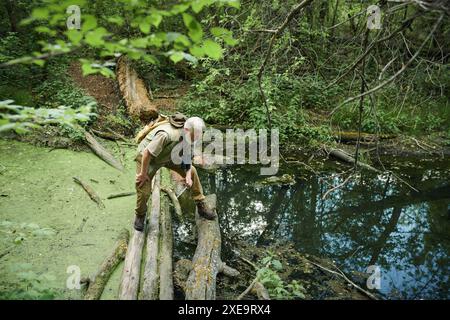 High angle view wide shot of senior Caucasian naturalist looking down into waters of mountain river, copy space Stock Photo