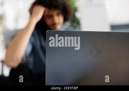 Start up company employee solving difficult business tasks and working on laptop in business office. Young arab project manager analyzing financial report statistics on computer Stock Photo