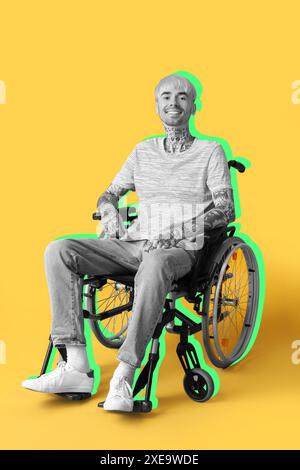 Happy young tattooed man sitting in wheelchair on yellow background Stock Photo