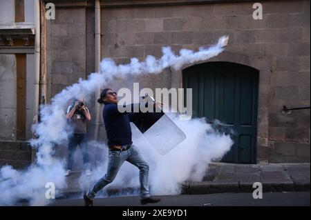 Demonstrators stand amid tear gas drifting across a street in Paris ...