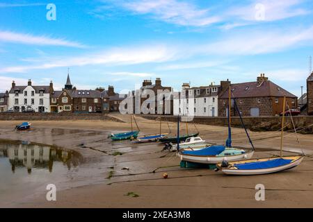 Stonehaven Harbour in Aberdeenshire is a picturesque scene of colourful boats nestled in the harbour, with a backdrop of historic buildings. Stock Photo