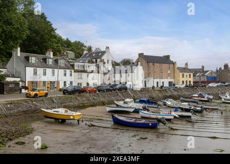 Stonehaven Harbour in Aberdeenshire is a picturesque scene of colourful boats nestled in the harbour, with a backdrop of historic buildings. Stock Photo