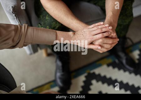 Top view of unrecognizable female psychologist holding hands with army veteran in therapy session copy space Stock Photo