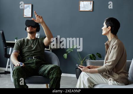 Portrait of army veteran using augmented reality technology in therapy session with female psychologist holding tablet Stock Photo