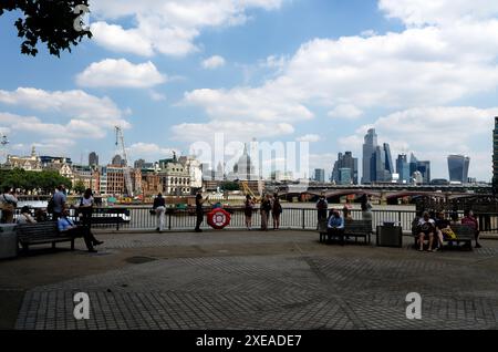 Tourists on the Southbank looking across the River Thames to St Pauls Cathedral and the City of London financial district. Stock Photo