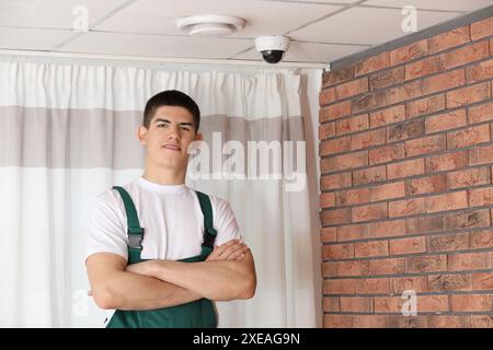 Installing CCTV camera. Portrait of technician indoors Stock Photo