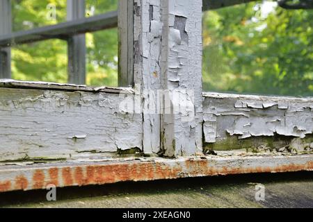 Wooden window frame damaged paint. Old window frame needing replacement. Paint job required. Old paint flaking. House maintenance needed concept. Stock Photo