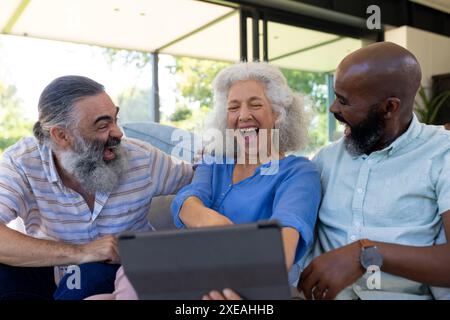 At home, Diverse group of friends laughing and watching something on tablet together Stock Photo