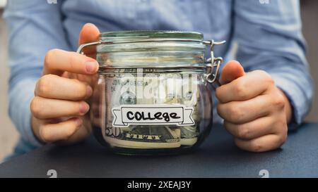 Unrecognizable woman holding Saving Money In Glass Jar filled with Dollars banknotes. COLLEGE transcription in front of jar. Man Stock Photo