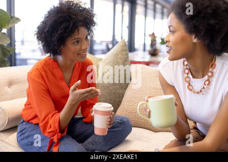 Women having casual business meeting, discussing ideas while holding coffee cups Stock Photo
