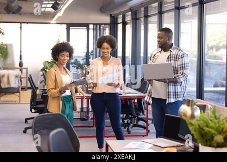 Discussing documents and using laptop, business team collaborating on project in office Stock Photo