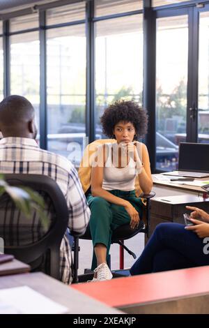 In office, businesswoman sitting and listening to colleagues during meeting Stock Photo