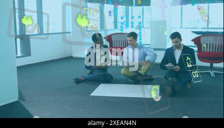 Image of green technology icons, diverse colleagues with laptop and tablet analyzing blueprint Stock Photo