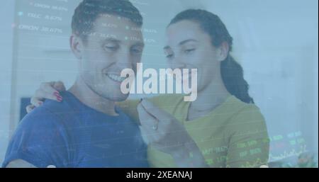 Image of graphs, trading board over caucasian woman holding key and kissing man at home Stock Photo