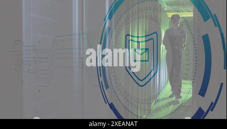 Image of shield, envelope, circles, asian male engineer walking and using laptop in server room Stock Photo