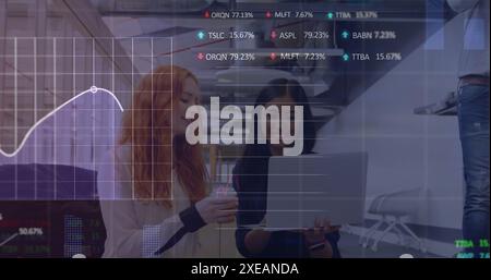 Image of statistical, stock market data processing over two diverse women discussing at office Stock Photo