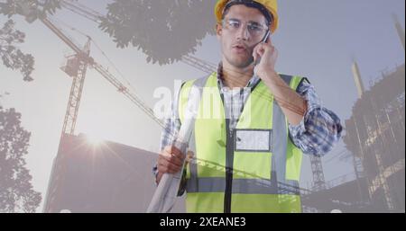 Image of building site over caucasian male worker talking on smartphone Stock Photo