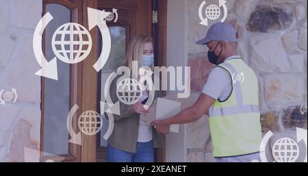 Image of media icons over caucasian woman with face mask taking package Stock Photo