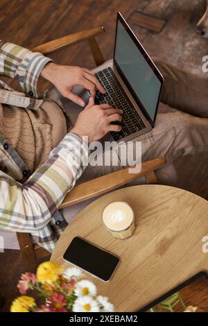 Vertical cropped portrait of man typing on laptop keyboard, freelancer working in cafe, using computer in coffee shop Stock Photo