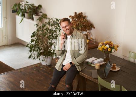 Portrait of handsome office manager, guy in co-working space, talking on mobile phone, calling someone, laughing and smiling, ha Stock Photo
