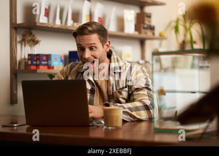 Lifestyle portrait of young businessman, freelancer sitting in cafe, drinking coffee and using laptop, working on online project Stock Photo