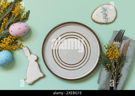 Table setting for Easter dinner with easter eggs and mimosa on a pastel background. Stock Photo