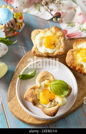 Scrambled eggs in puff pastry with cheese and bacon. Easter breakfast on a festive table. Stock Photo