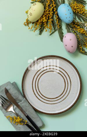 Table setting for Easter dinner with easter eggs and mimosa on a pastel background. Stock Photo